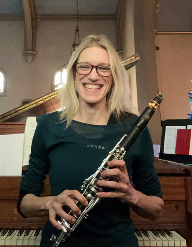 Lesson Teacher in Pittsburgh holding clarinet by the piano.